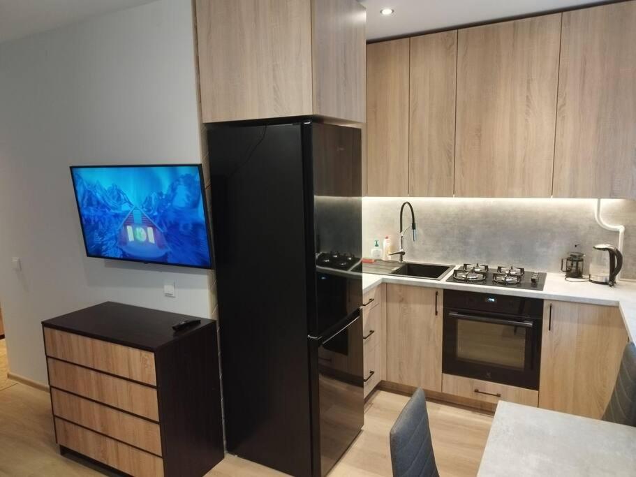 uma cozinha com um frigorífico preto e uma televisão em Rami vieta visiems atvejams. em Vilnius