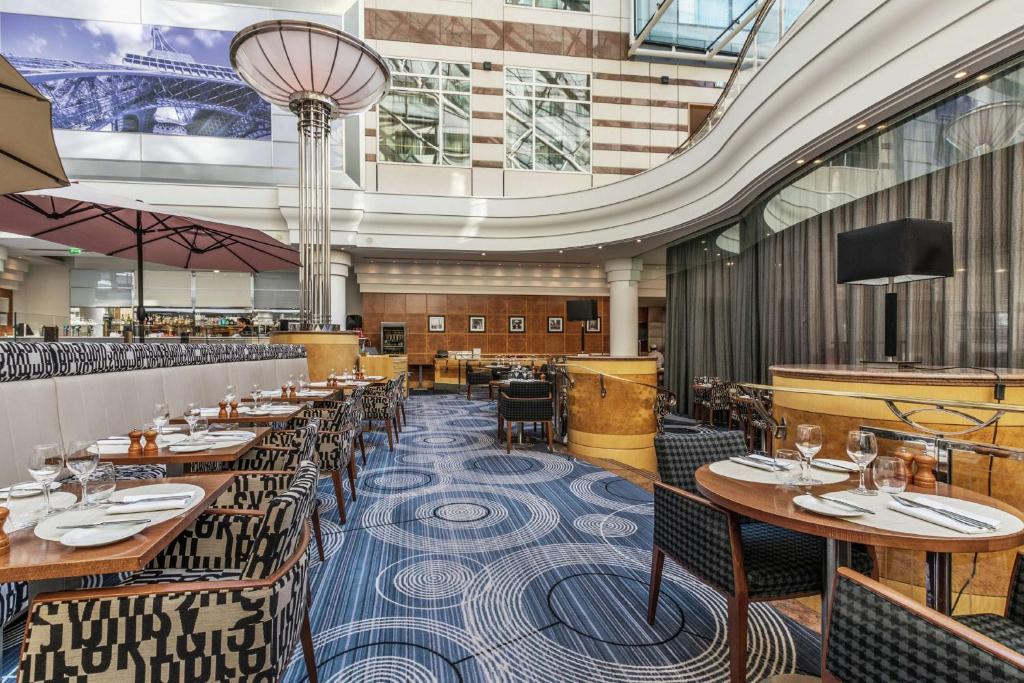 a restaurant with tables and chairs and a ceiling at Hilton Paris Charles De Gaulle Airport in Roissy-en-France