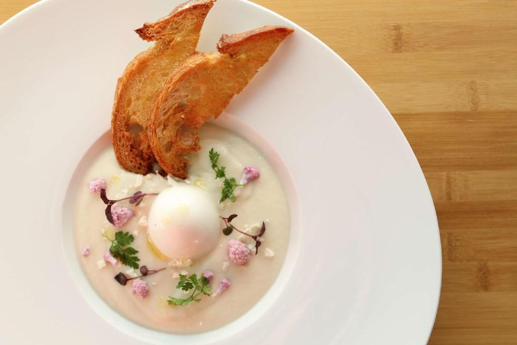 a white plate with a egg and a piece of bacon at Hilton Paris Charles De Gaulle Airport in Roissy-en-France
