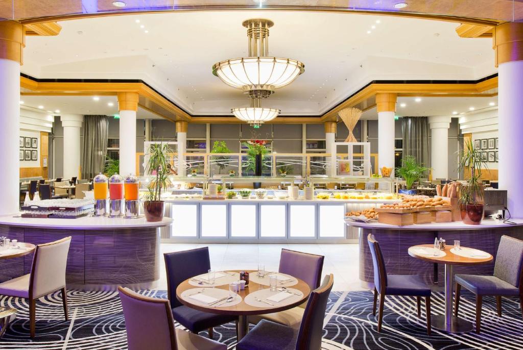 a restaurant with tables and chairs and a bar at Hilton Paris Charles De Gaulle Airport in Roissy-en-France