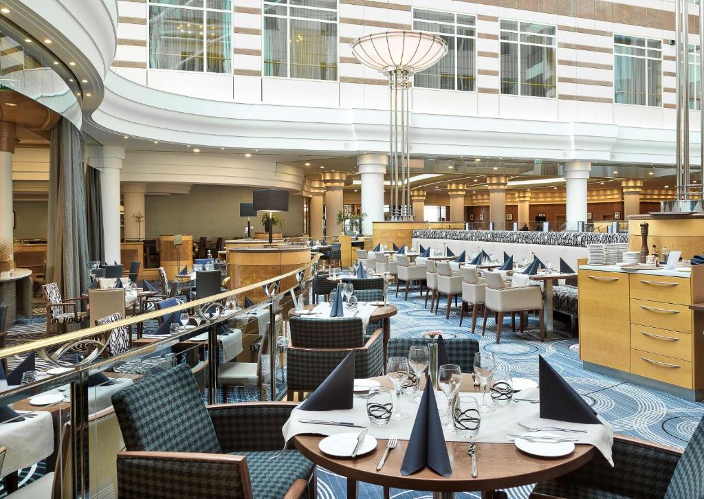 a restaurant with tables and chairs in a building at Hilton Paris Charles De Gaulle Airport in Roissy-en-France