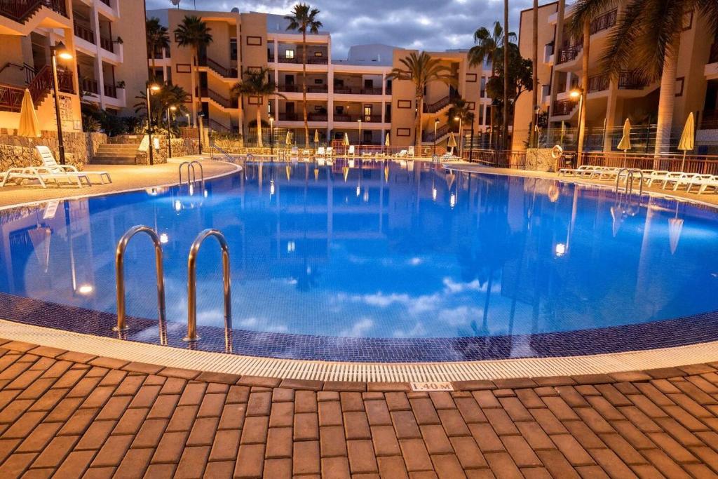 ein großer blauer Swimmingpool vor Gebäuden in der Unterkunft Apartamento Balandros in Palm-mar
