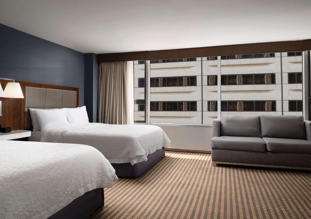 a hotel room with two beds and a couch and a window at Hampton Inn Chicago Downtown/Magnificent Mile in Chicago