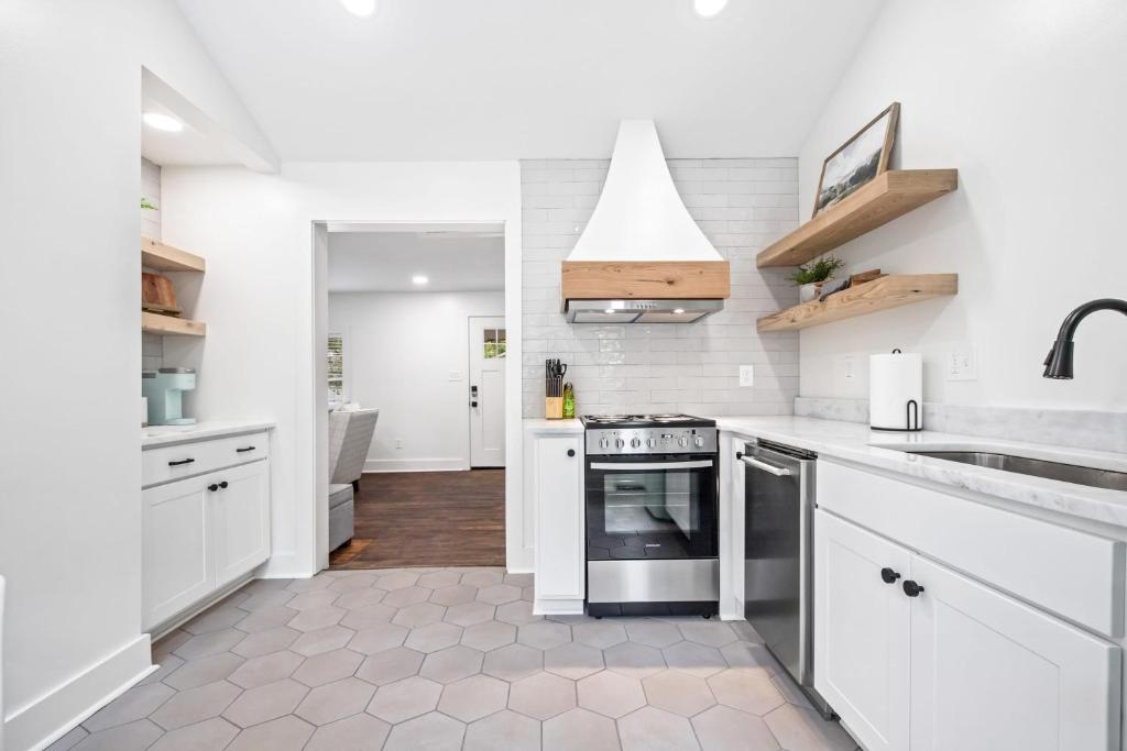 uma cozinha com armários brancos e um forno com placa de fogão em Saints Street Cottage em Lafayette
