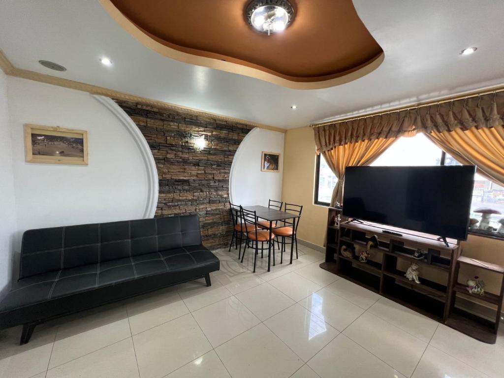 a living room with a couch and a flat screen tv at Hermoso y acogedor departamento in Atuntaqui