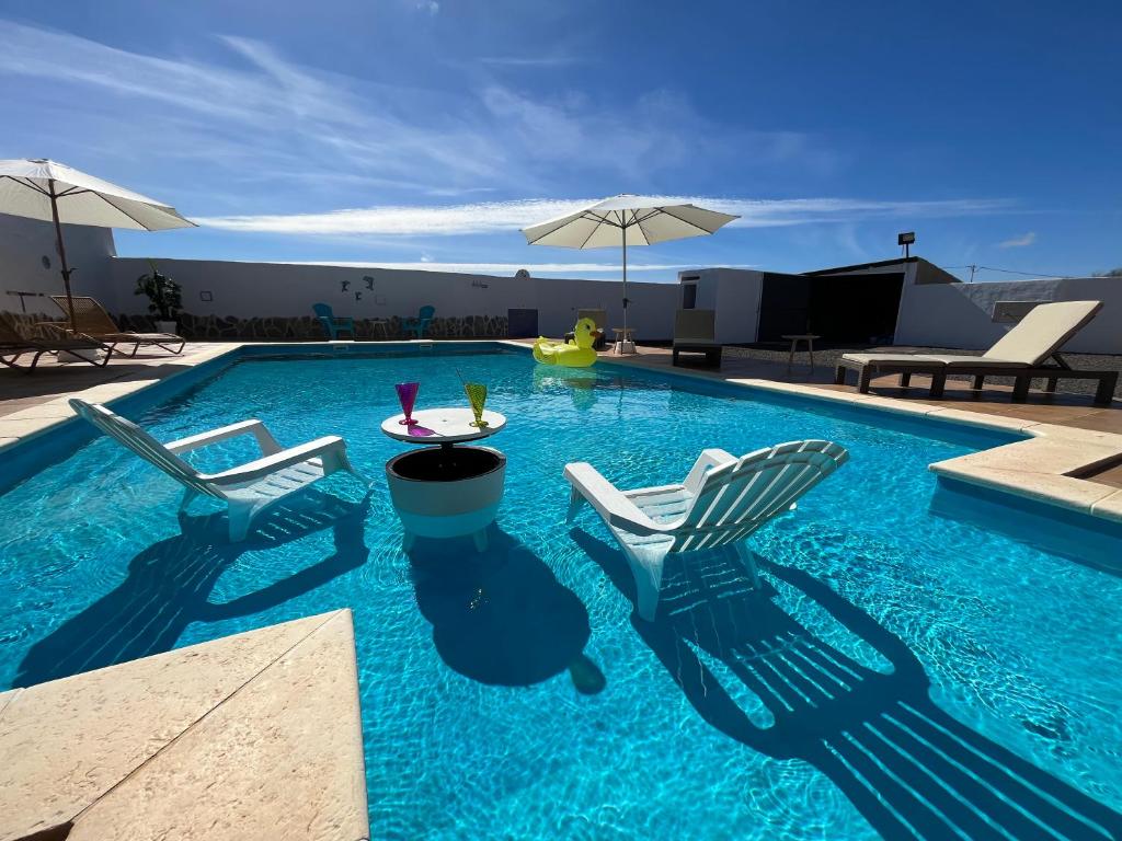 a swimming pool with chairs and a table and an umbrella at Casa Noa in Tuineje