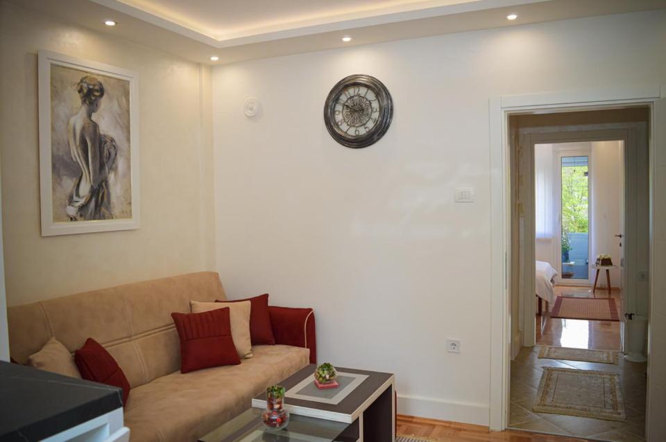 - un salon avec un canapé et un réveil sur le mur dans l'établissement River Site Lux Apartment, à Podgorica