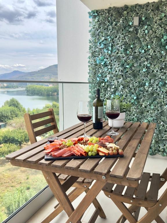 una mesa de picnic con copas de vino y un plato de comida en Douro Escape - Riverfront Apartment en Peso da Régua