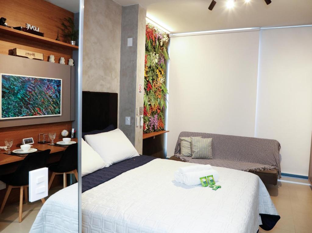 ein Schlafzimmer mit einem Bett, einem Tisch und einem Gemälde in der Unterkunft C1 Estúdio VN1 - A 400 metros do Allianz Parque in São Paulo