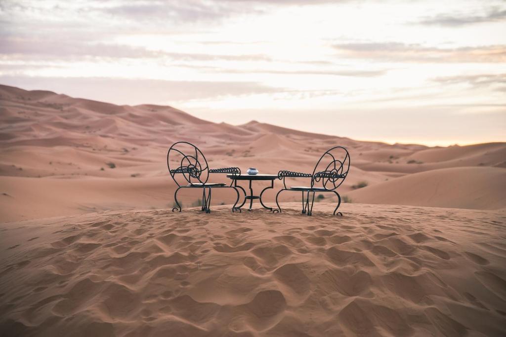 メルズーガにあるMerzouga Luxury Desert camp, excursion and activitiesの砂漠の椅子2脚とテーブル