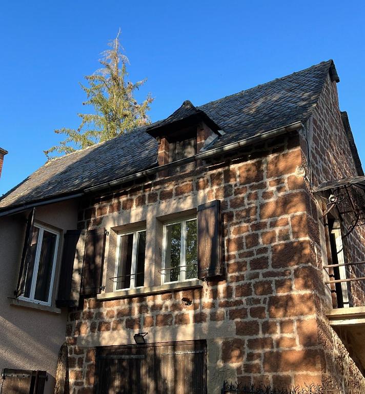 une ancienne maison en briques avec deux fenêtres et un toit dans l'établissement Petit maison du Vallon, à Marcillac-Vallon