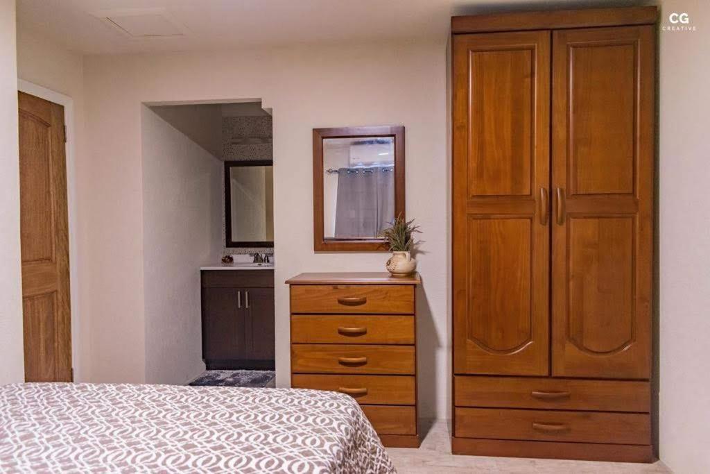 a bedroom with a dresser and a large wooden cabinet at SkylineSuites Lost in Paradise - FA3 in Grand Anse