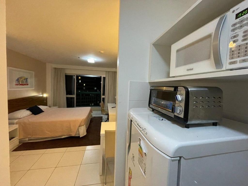 Habitación con cama y cocina con microondas. en V1117 Lindo flat aconchegante em Hotel de BSB en Brasilia