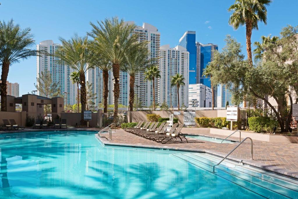 a swimming pool with palm trees and a city skyline at Hilton Grand Vacations Club Paradise Las Vegas in Las Vegas