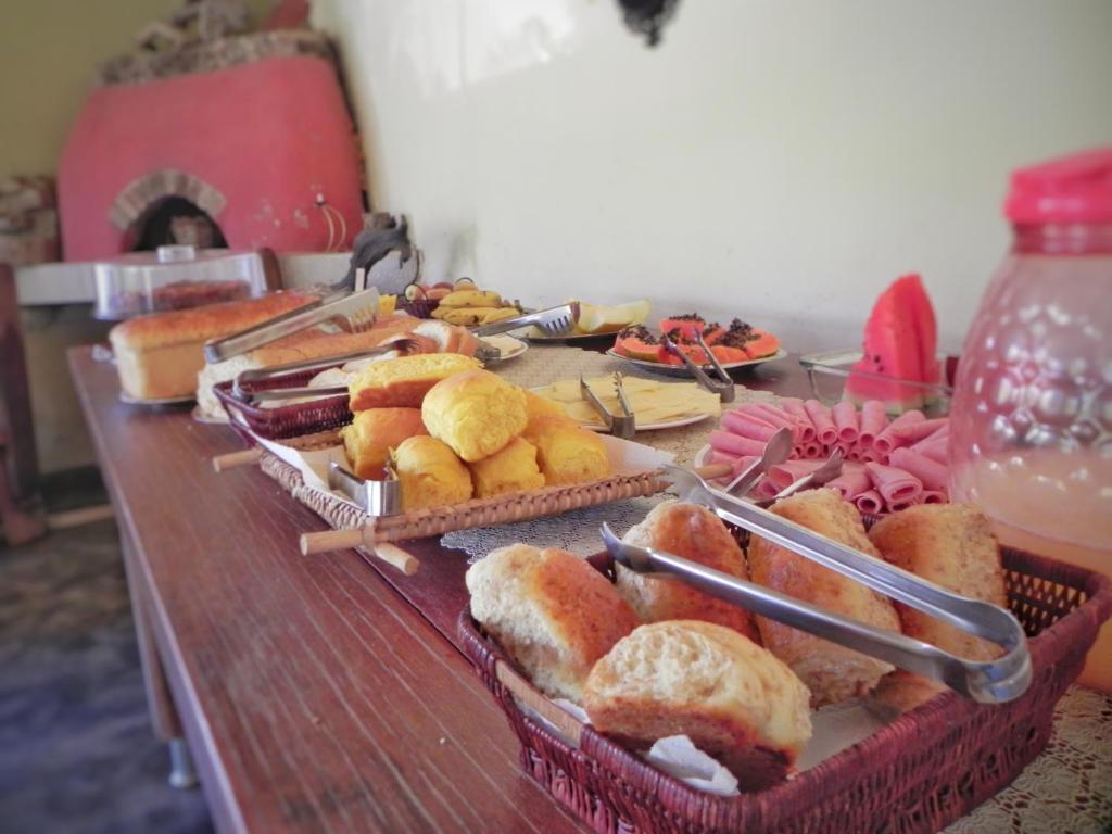 a table with several baskets of bread and pastries at Pousada Éden - Conforto, Imersão e Natureza in Sao Jorge