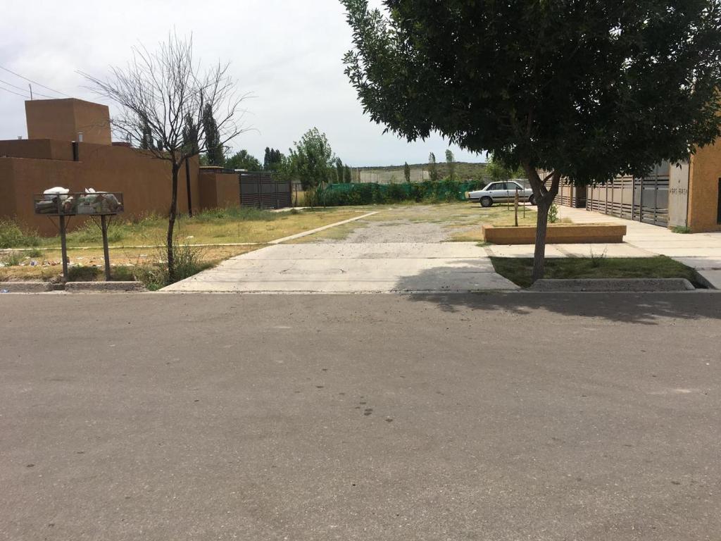 un estacionamiento vacío con un árbol y un edificio en Apartamiento acogedor y familiar cerca Del Río en Tunuyán