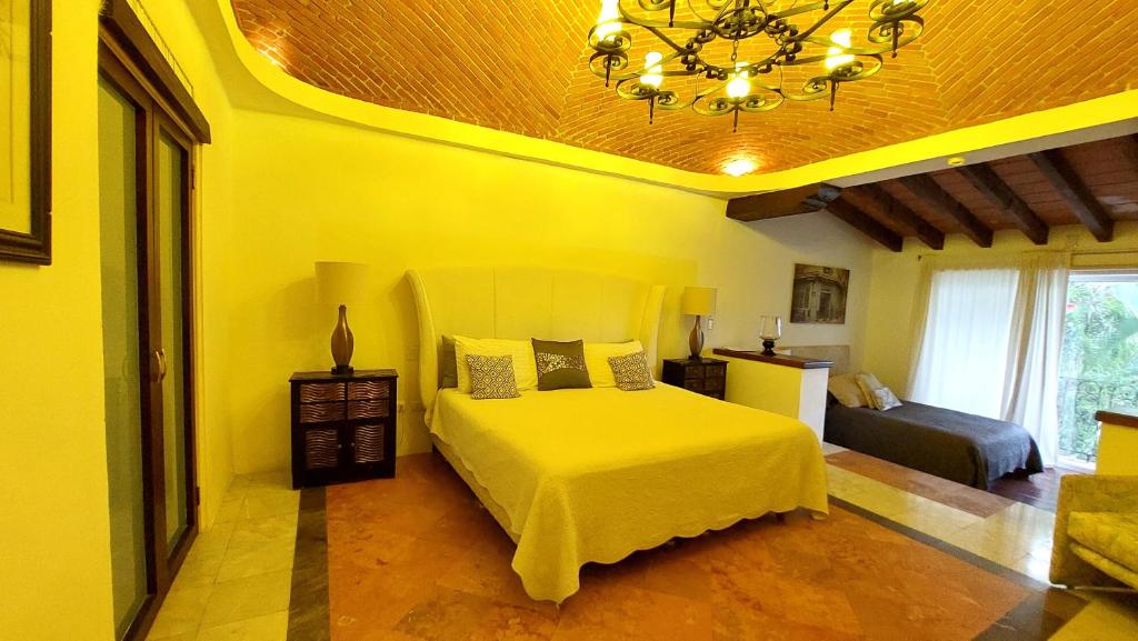 a yellow bedroom with a bed and a chandelier at La Villa du Golf à Cancun Hotel Boutique in Cancún
