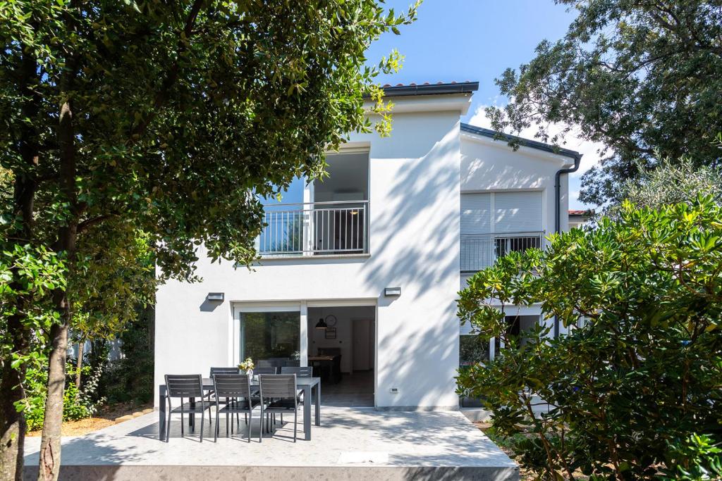 a white house with black chairs and trees at Holiday house Bibi in Punat