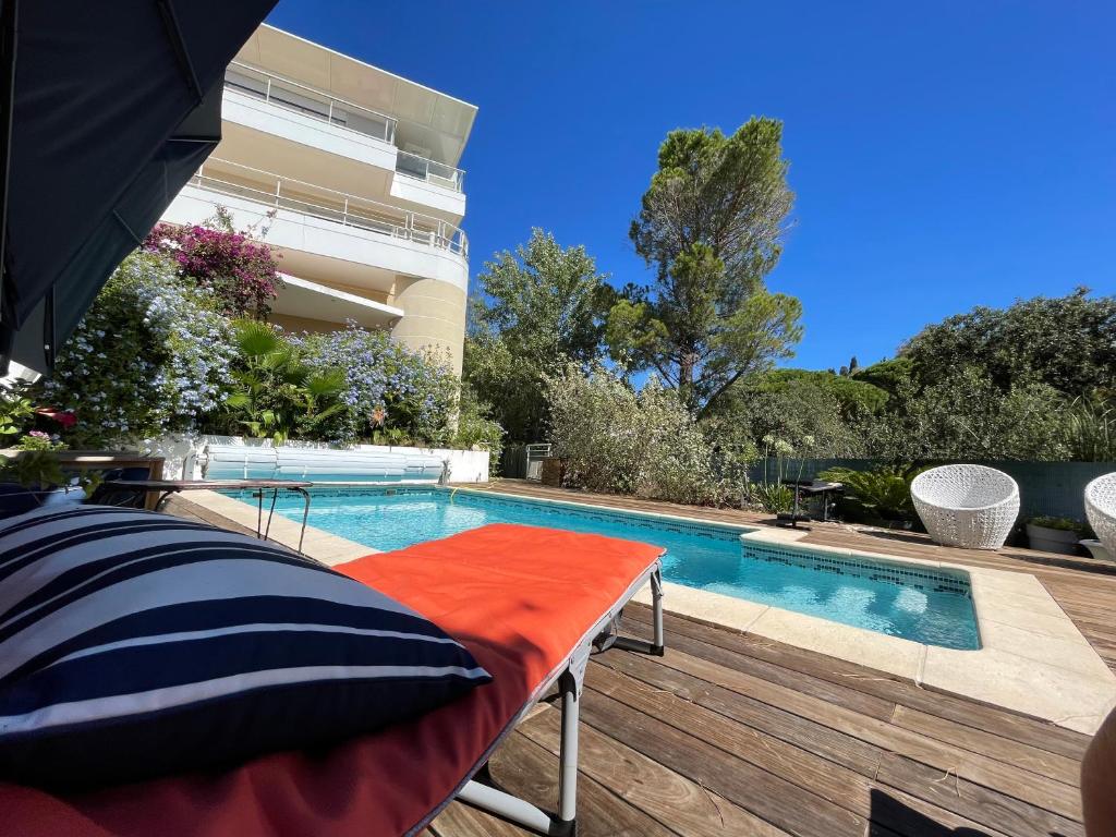 a swimming pool with a bed and an umbrella at Villa Les Voiles in Cannes