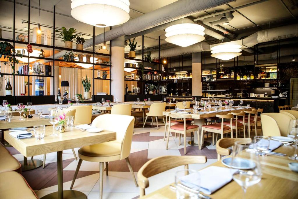 a restaurant with tables and chairs and a bar at Hilton Munich City in Munich