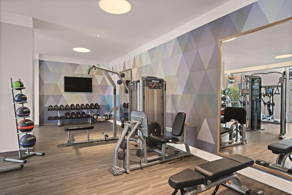 a gym with several tread machines and a mirror at Hilton Munich City in Munich