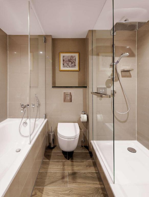 a bathroom with a tub and a toilet and a shower at Hilton Munich City in Munich