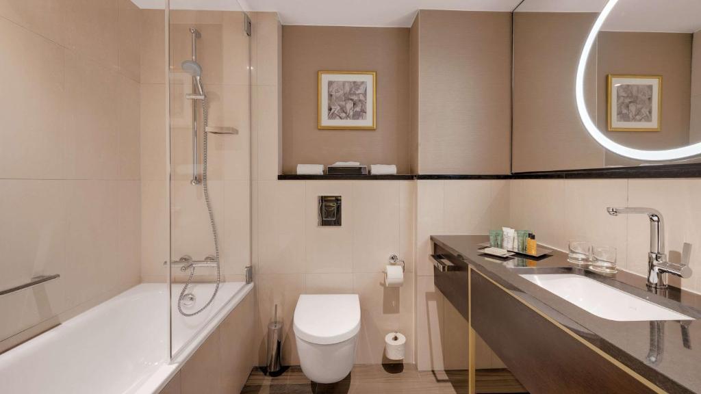 a bathroom with a tub and a toilet and a sink at Hilton Munich City in Munich