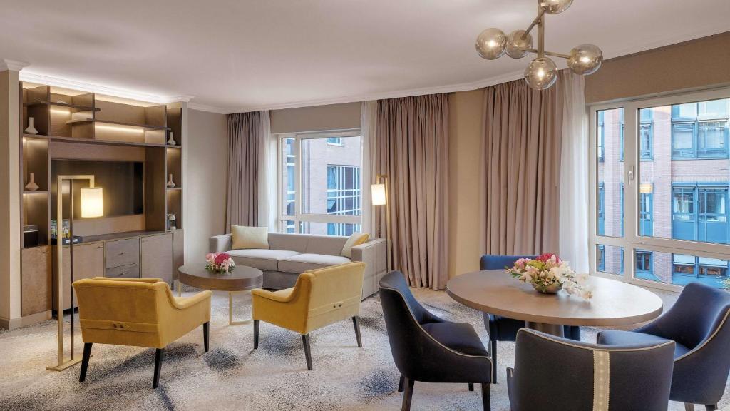 a living room with a couch and a table and chairs at Hilton Munich City in Munich