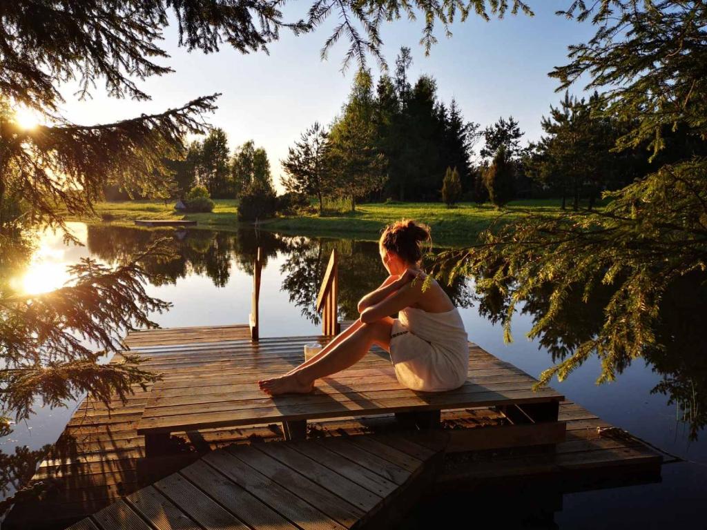 une femme assise sur un quai à côté d'un lac dans l'établissement Kliukai, à Dubingiai