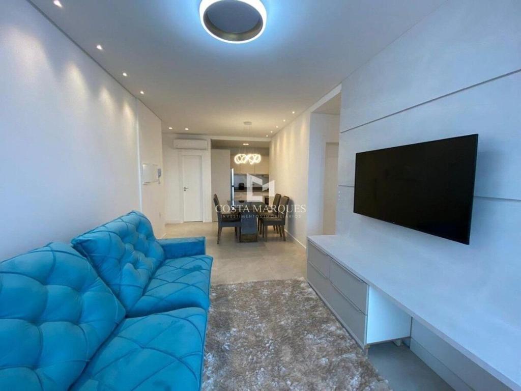 sala de estar con sofá azul y TV de pantalla plana en Apartamento em Bombas, en Bombinhas