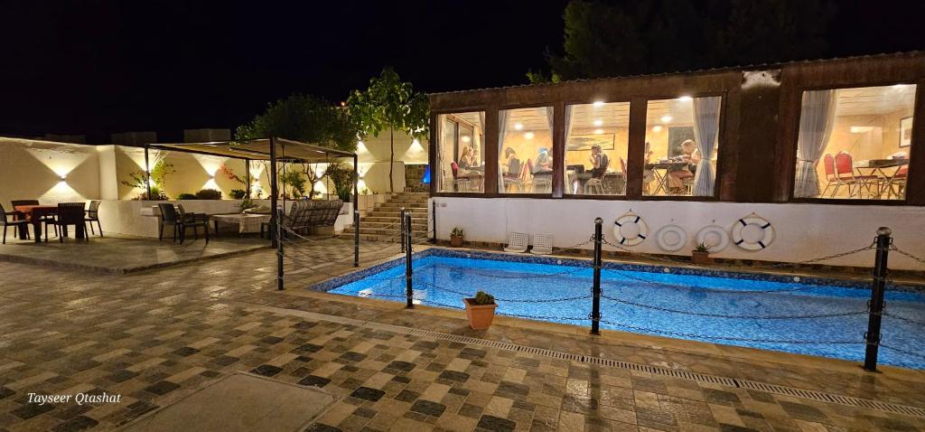uma piscina em frente a um edifício à noite em Al Namteh Lodge em ‘Ābil