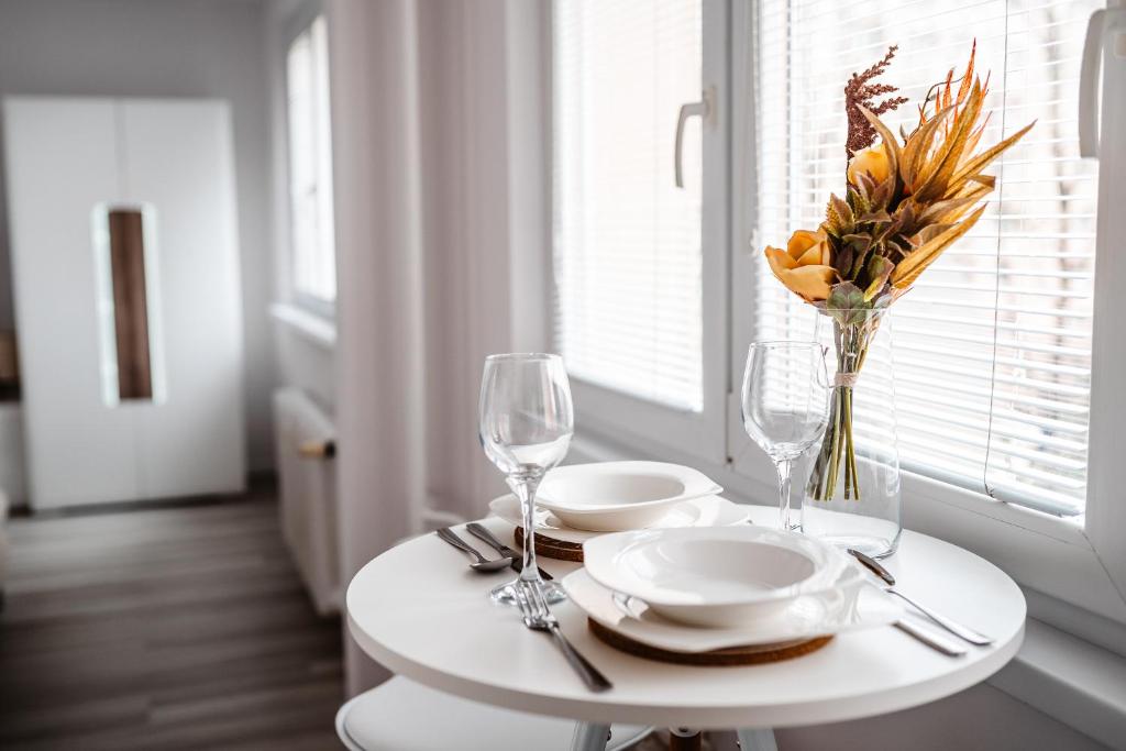 a table with plates and glasses and a vase of flowers at Apartmán Nová Nemocnica 10min. pešo do Centra in Košice