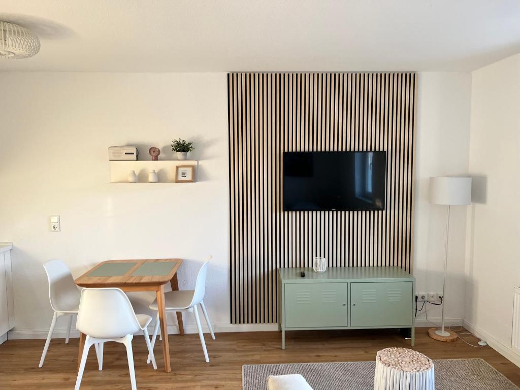 a living room with a table and a television on a wall at Smultron Apartment Altstadt Wismar in Wismar