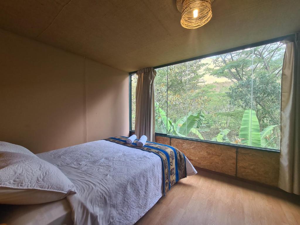a bedroom with a large window with a bed in it at Araplay Lodge in Santa Teresa