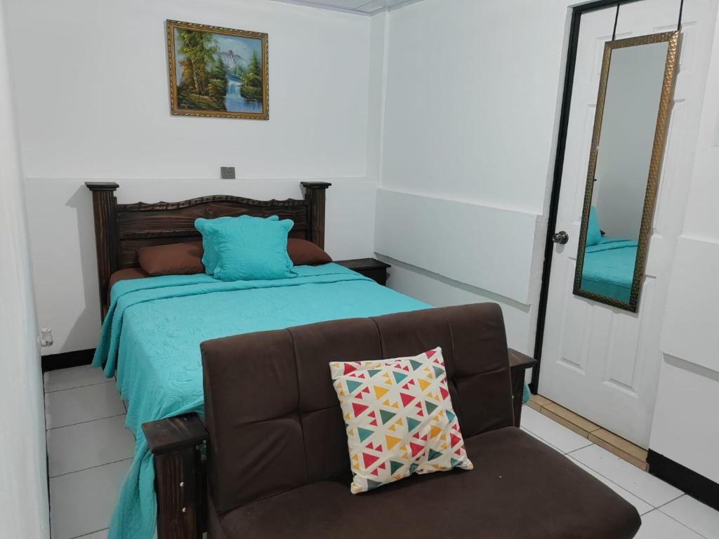 1 dormitorio con cama, sofá y espejo en Gran Hotel Desamparados, en Desamparados