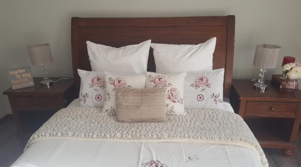 1 cama con almohadas blancas y rosas y 2 mesitas de noche en Charis on Beaumont en Margate