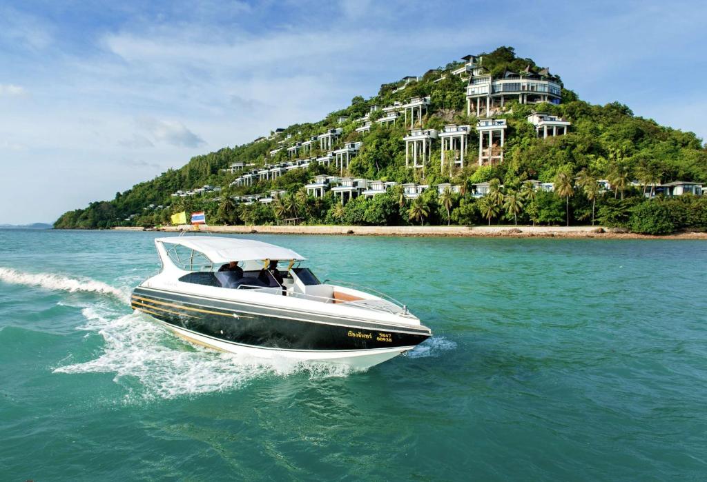 a boat in the water with an island in the background at Conrad Koh Samui Residences in Taling Ngam Beach