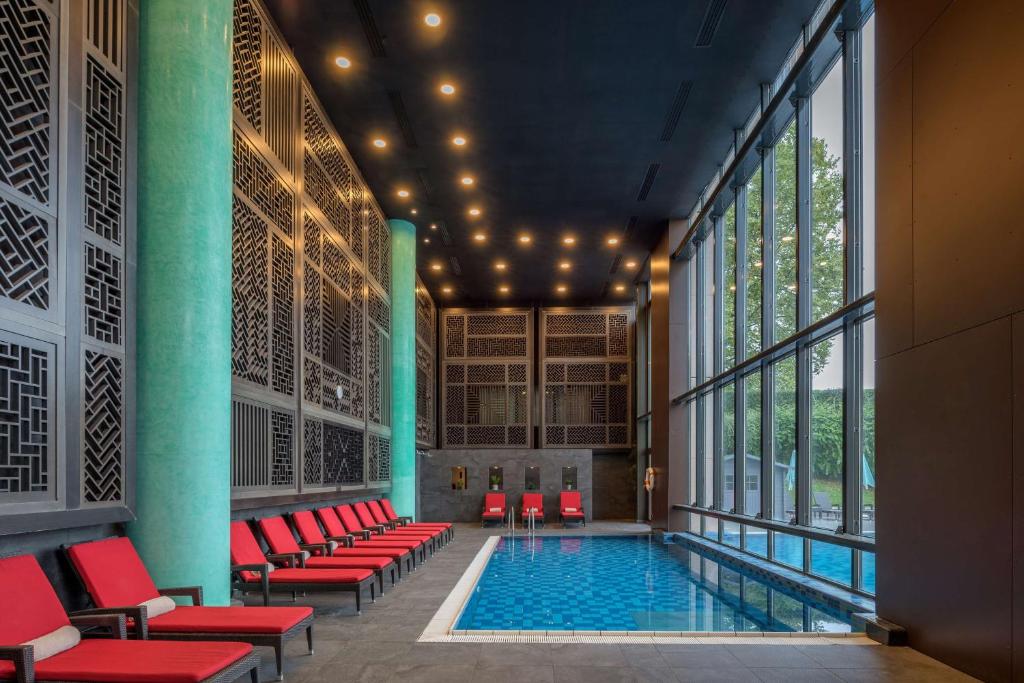 a pool in a building with red chairs at Hilton Evian Les Bains in Évian-les-Bains