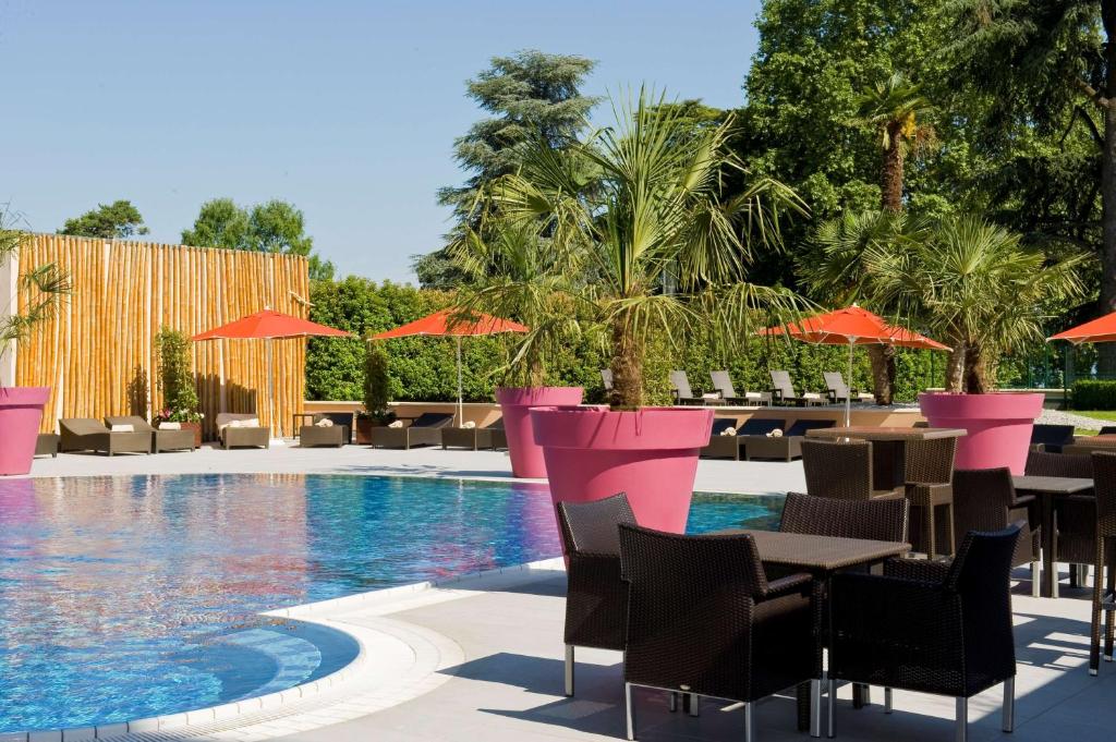 a resort with a pool and tables and chairs at Hilton Evian Les Bains in Évian-les-Bains