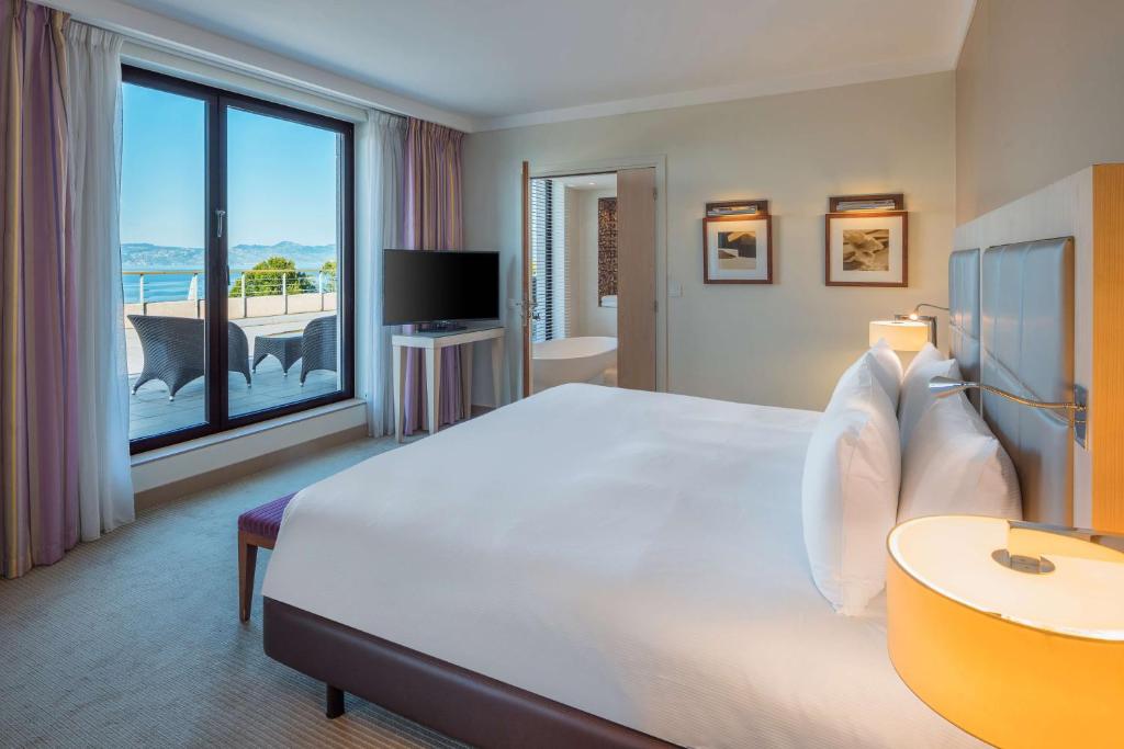 a bedroom with a large bed and a large window at Hilton Evian Les Bains in Évian-les-Bains