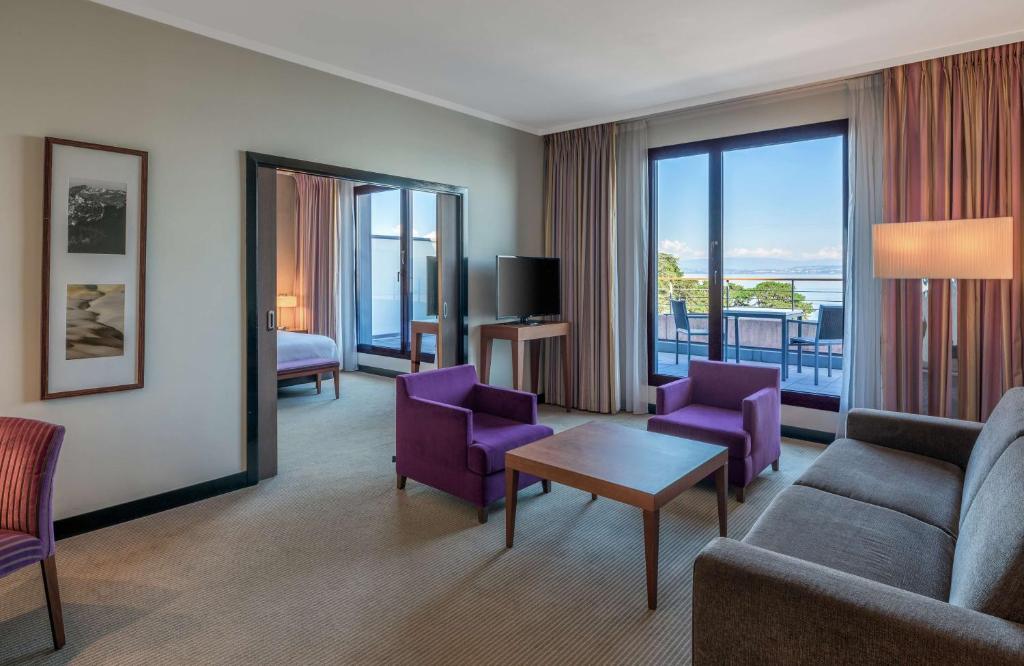 a living room with purple furniture and a large window at Hilton Evian Les Bains in Évian-les-Bains
