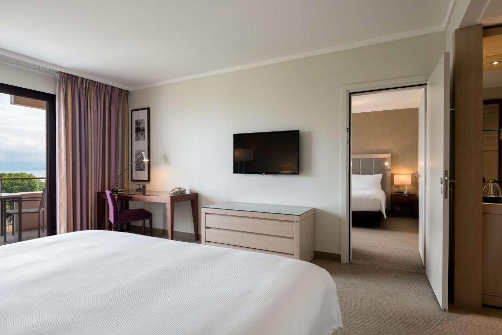 a hotel room with a bed and a desk with a television at Hilton Evian Les Bains in Évian-les-Bains