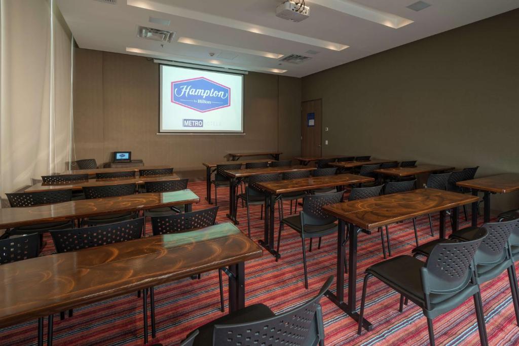 a room with tables and chairs and a projection screen at Hampton By Hilton Valledupar in Valledupar
