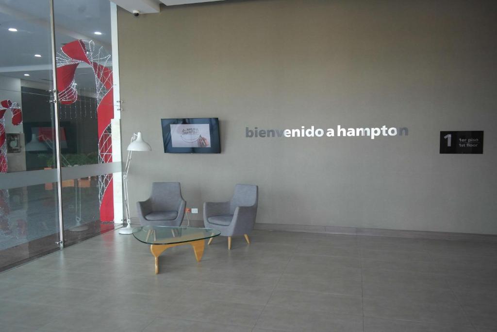 two chairs and a table in a room with a sign at Hampton By Hilton Valledupar in Valledupar