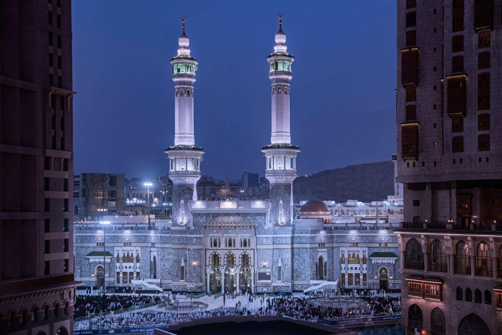 a building with two tall towers in a city at night at Conrad Makkah in Mecca