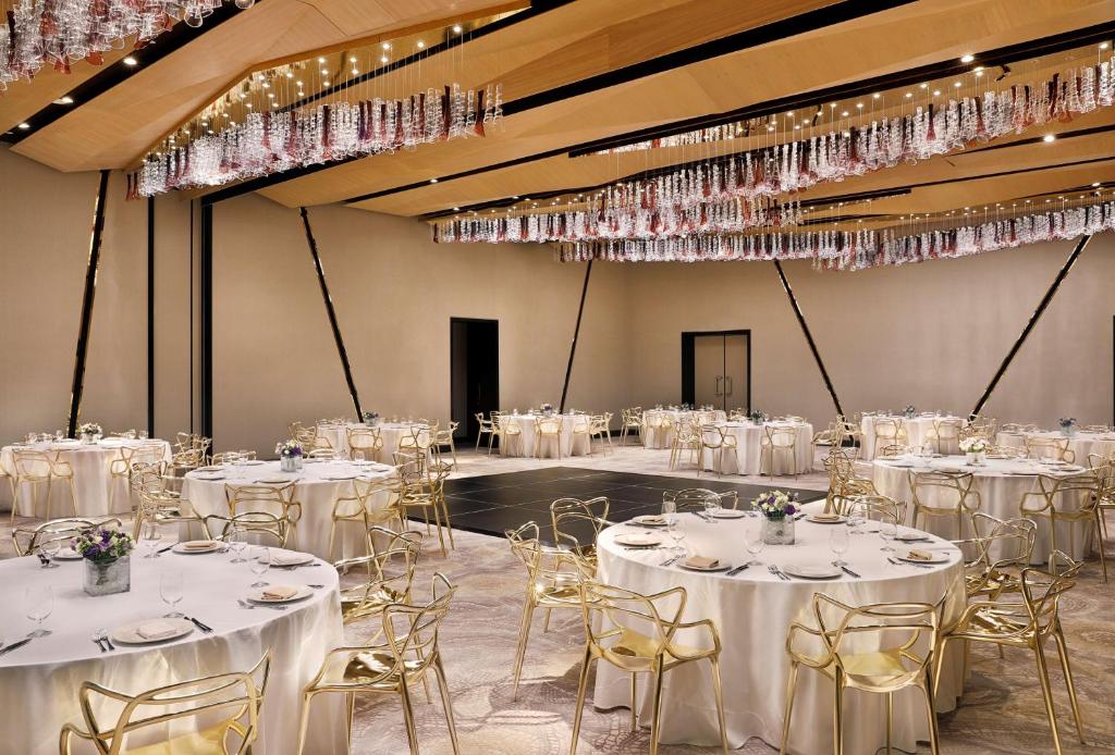 einen Bankettsaal mit weißen Tischen, Stühlen und Kronleuchtern in der Unterkunft AlRayyan Hotel Doha, Curio Collection by Hilton in Doha