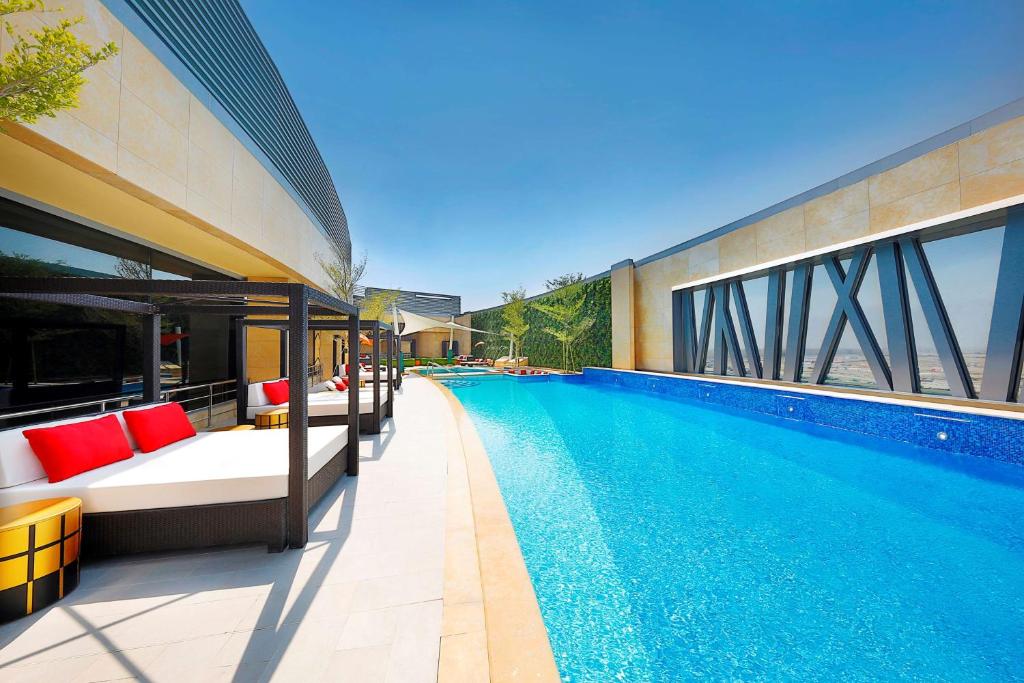 ein Pool neben einem Gebäude in der Unterkunft AlRayyan Hotel Doha, Curio Collection by Hilton in Doha