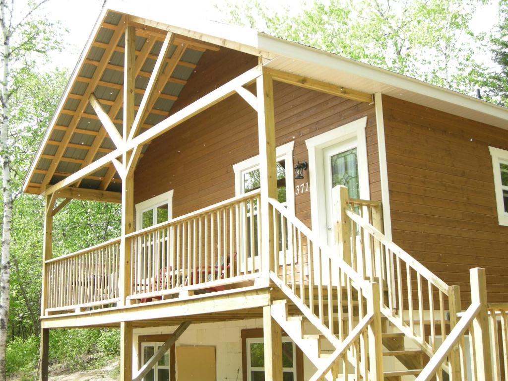 a house with a large deck on the side of it at Chalet des Noisetiers in Tadoussac