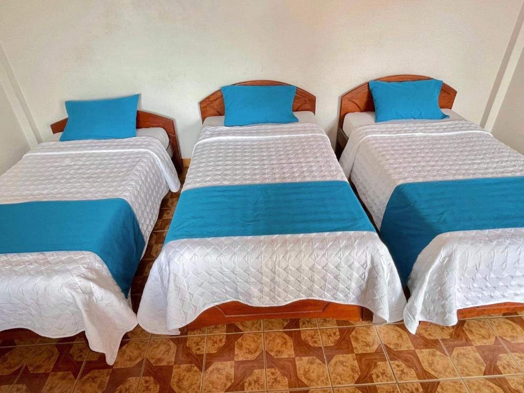three beds in a room with blue pillows on them at Hotel Firenze in Tarapoto