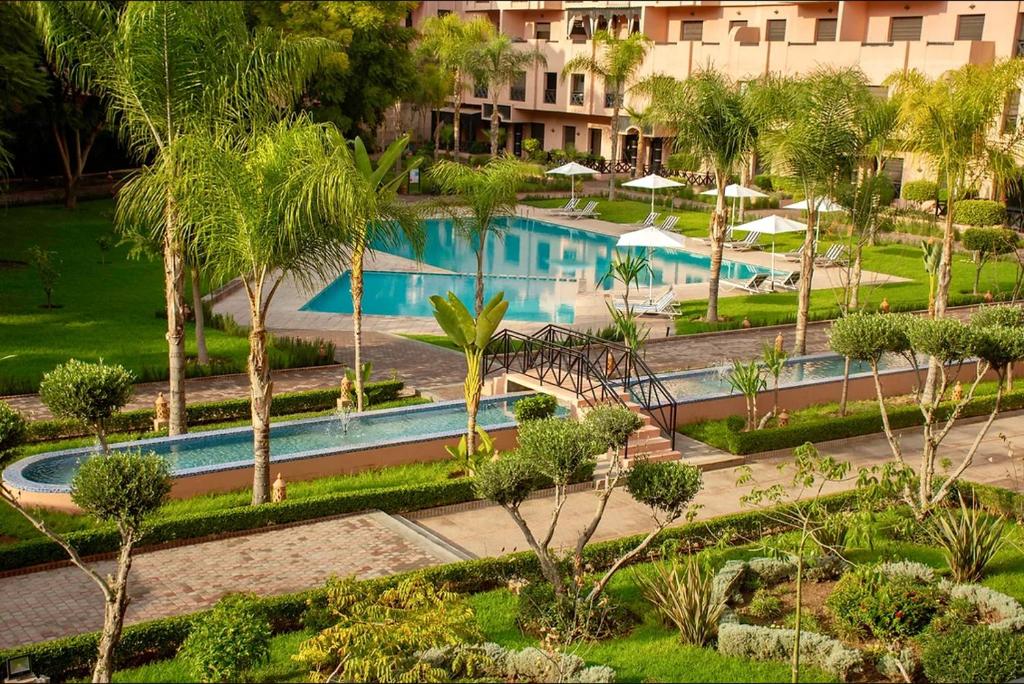 - une vue aérienne sur la piscine du complexe bordée de palmiers dans l'établissement APPARTEMENT COSY Au PALMERAIE VILLAGE - 5 PISCINES, à Marrakech